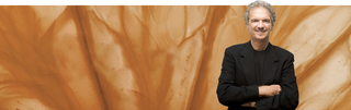 dr.goldfaden standing with arms crossed in front of brownish orange background