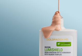 Goldfaden MD Lumishield sunscreen bottle with a beige droplet on a light blue background